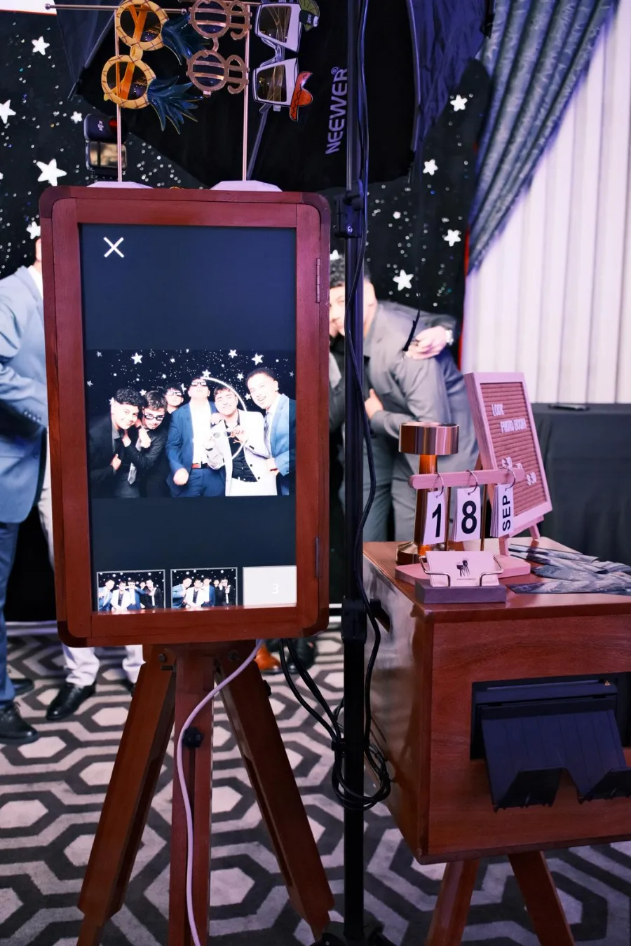 Guests posing on the booth screen, with the printer and event sign beside it